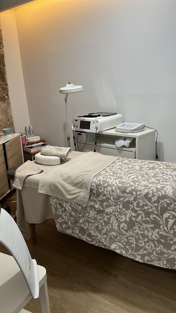 Cabina de tratamiento con camilla, equipos estéticos y pared blanca
