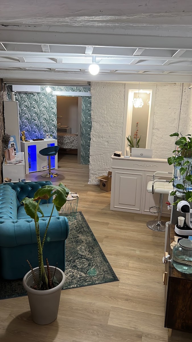 Vista general del salón con zona de manicura, plantas, techo blanco con vigas y suelo de madera