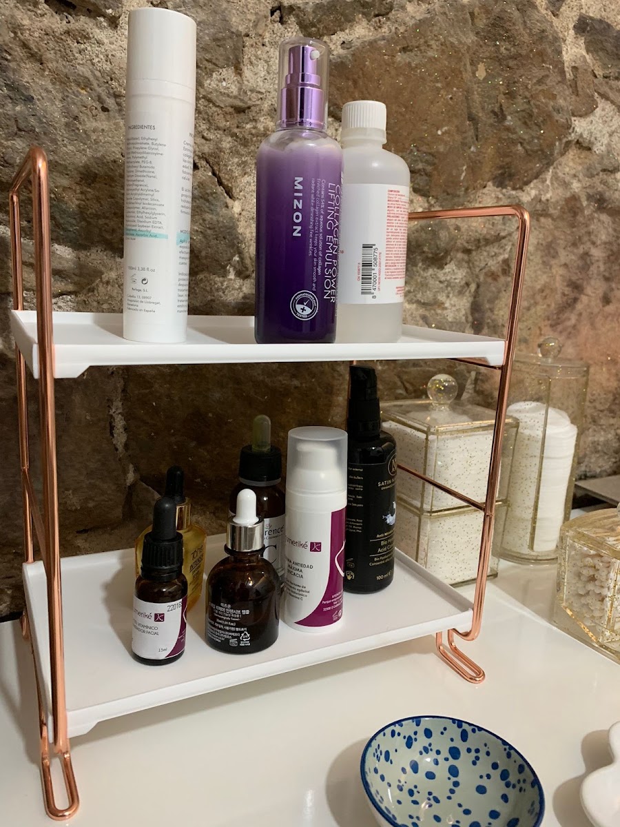 Estantería de cobre con productos cosméticos profesionales sobre pared de piedra